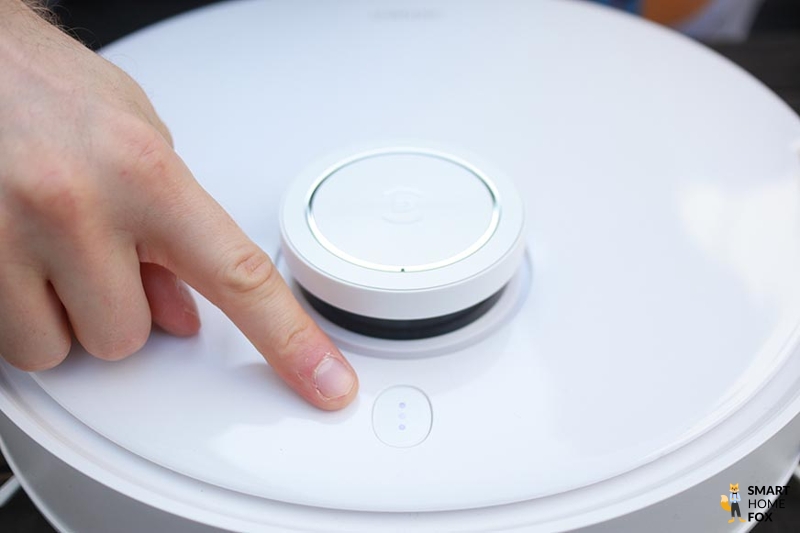 Der Finger zeigt auf den Hochglanz-Deckel des Ecovacs Deebot T10
